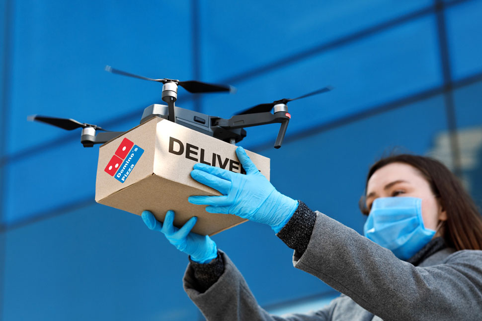 Hình ảnh người phụ nữ chuẩn bị thả thiết bị giao hàng thông minh đang chở khối hàng của Domino's Pizza 