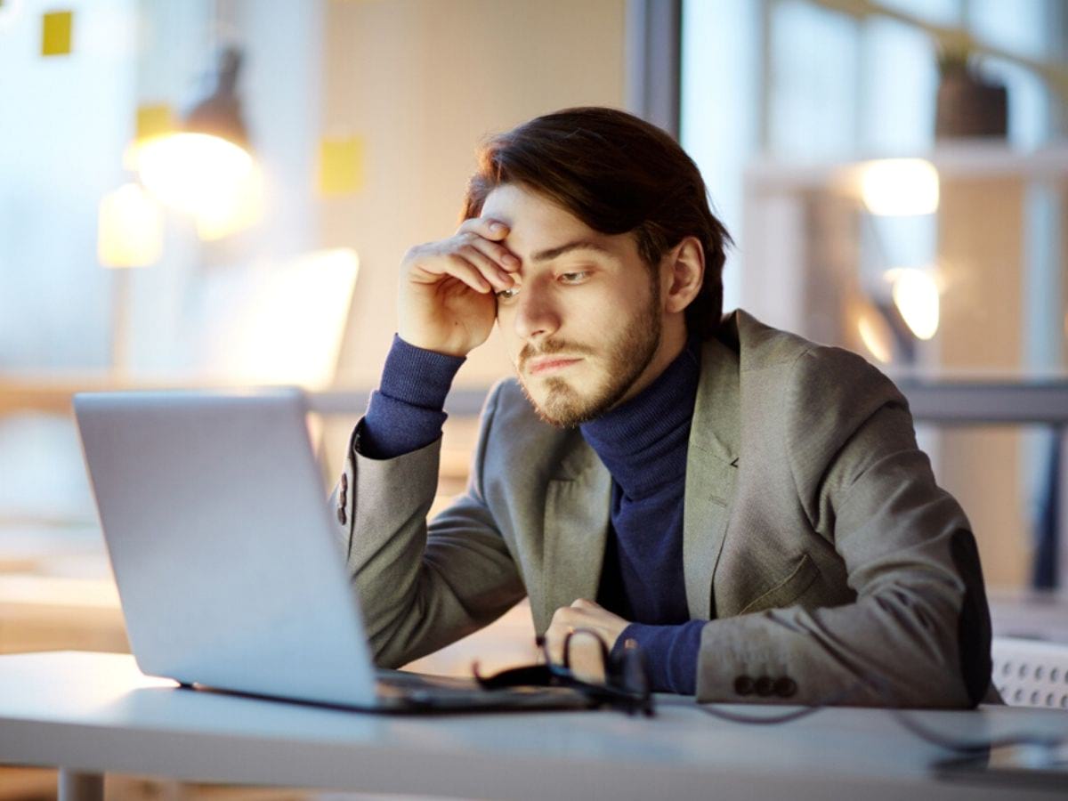 Người đàn ông ngồi trước máy tính và đọc thư điện tử của mình.