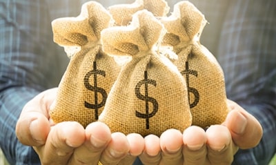 1 người đang nâng trên tay các túi tiền