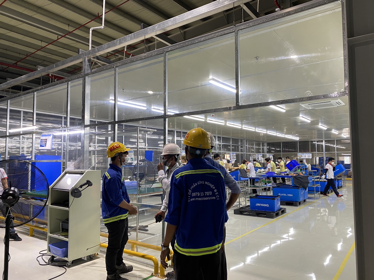 2 kỹ thuật đang đứng nói chuyện với khách hàng bên trong nhà máy