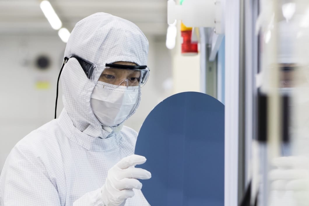Một kỹ thuật viên mặc đồ bảo hộ tại phòng sạch khi kiểm tra sản xuất thành phẩm