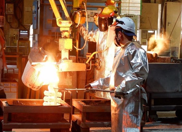 Kỹ thuật viên đang đổ khuôn phôi bằng kim loại đang nóng chảy