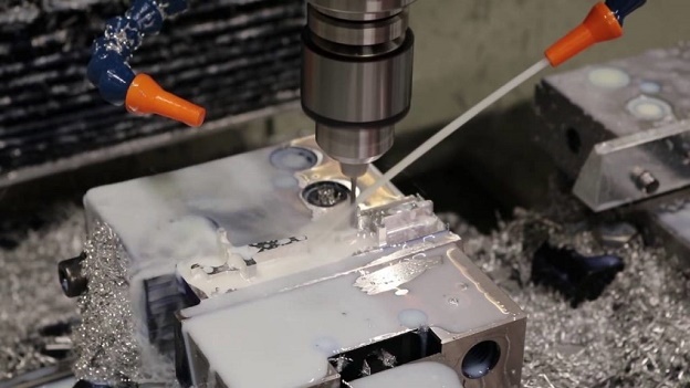 Máy cắt thực hiện tiện kim loại, có vòi nước liên tục xịt vào làm ướt bột kim loại, tránh bụi mịn