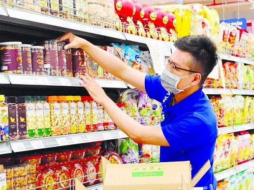 Nhân viên siêu thị đang xếp hàng đã được đóng gói sẵn lên kệ trưng bày