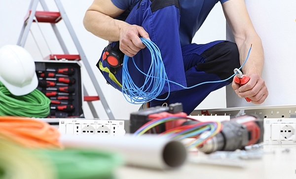 Thợ điện đang dùng kiềm cắt dây điện, xung quanh có rất nhiều công cụ làm việc khác