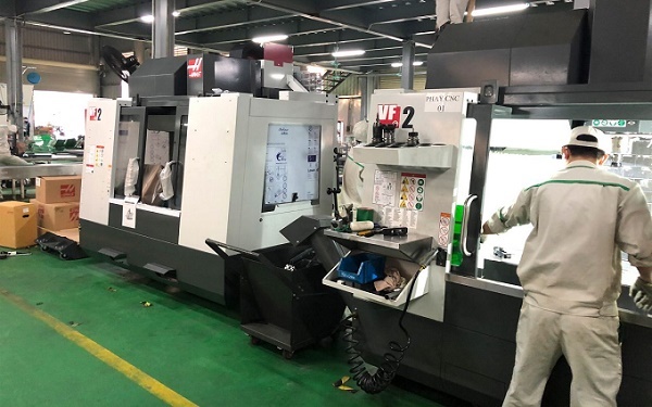 Nhân viên đang vận hành máy CNC trong nhà máy để gia công cơ khí