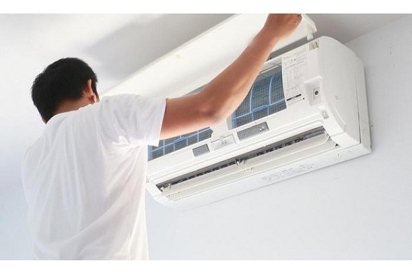 Người đàn ông đang mở nắp máy lạnh kiểm tra lưới lọc bên trong