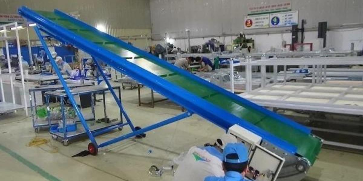 Các nhân viên làm việc bên cạnh một băng tải cao su trong nhà xưởng