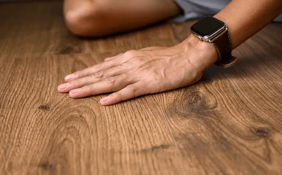 Bàn tay chạm vào sàn gỗ để cảm nhận chất liệu và đo lường kích thước, khoảng cách