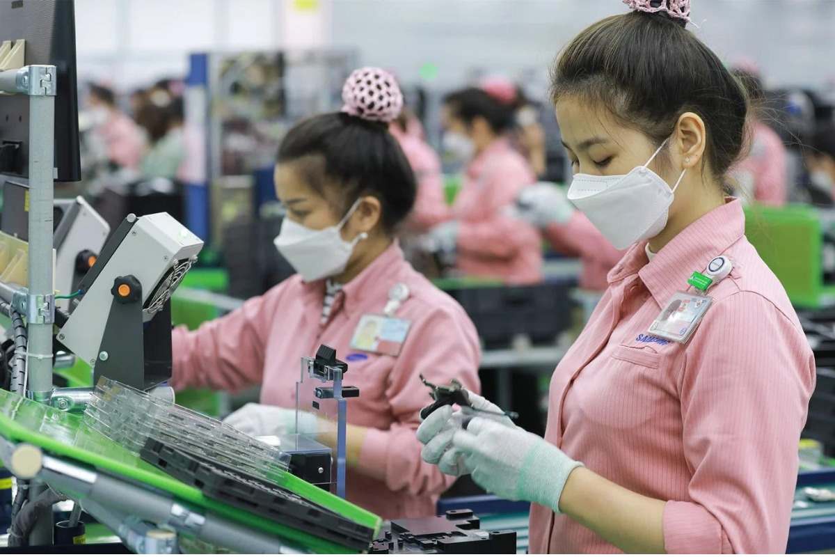 Nhiều công nhân nữ mặc đồng phục bảo hộ màu hồng đang làm việc trong dây chuyền sản xuất