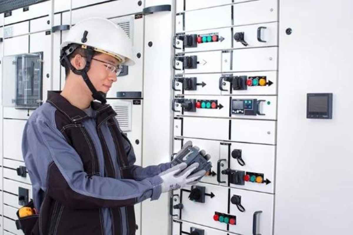 Kỹ thuật viên đang đứng bên cạnh kiểm tra chỉ số của tủ điện