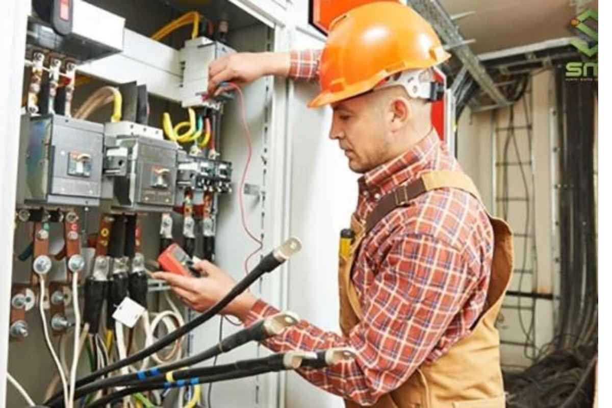 Kỹ thuật viên đang kiểm tra điện bên trong tủ điện công nghiệp