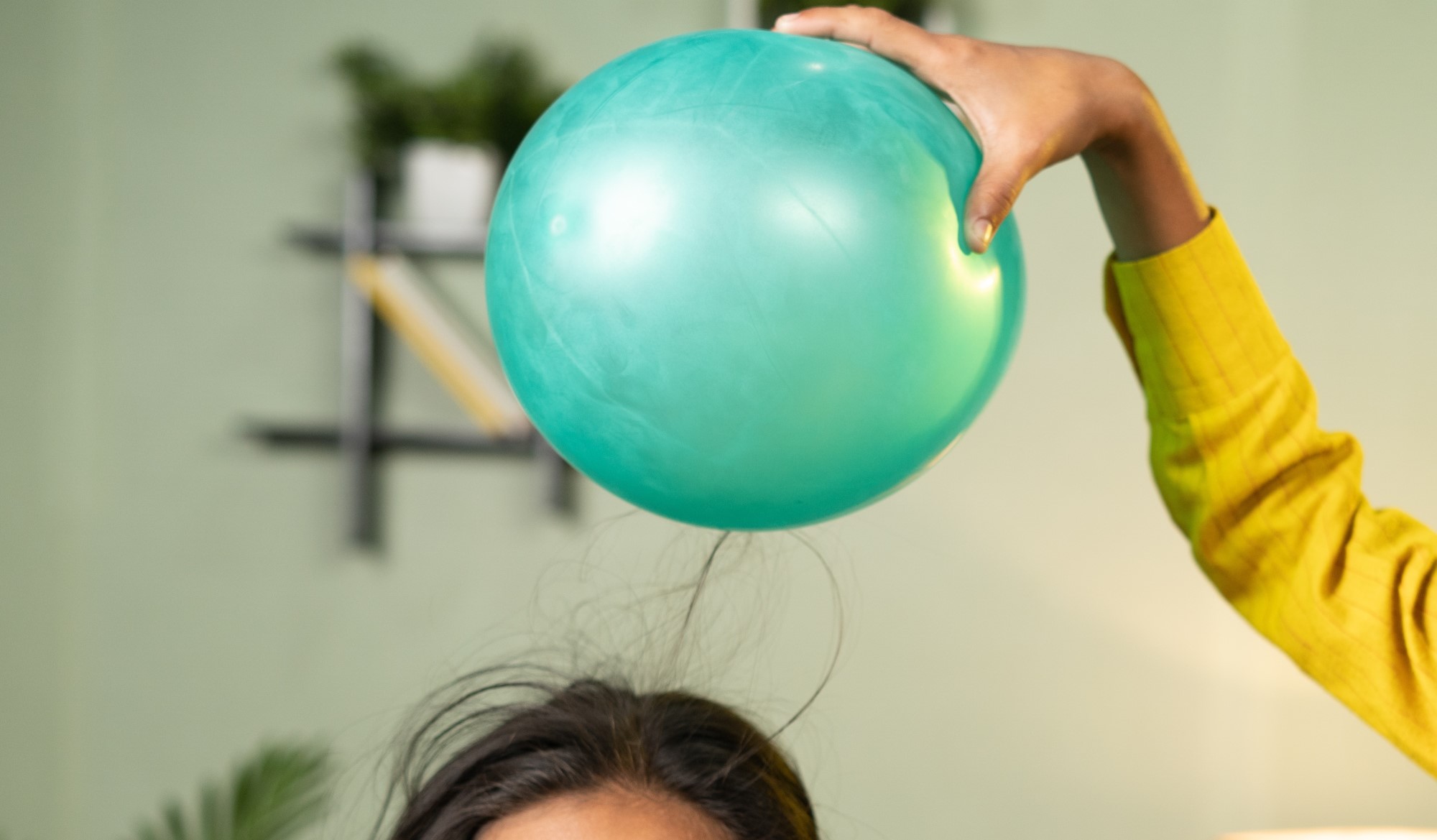 Bé gái có mái tóc vàng xoăn bị dựng lên do tĩnh điện từ quả bóng bay ở trên đầu