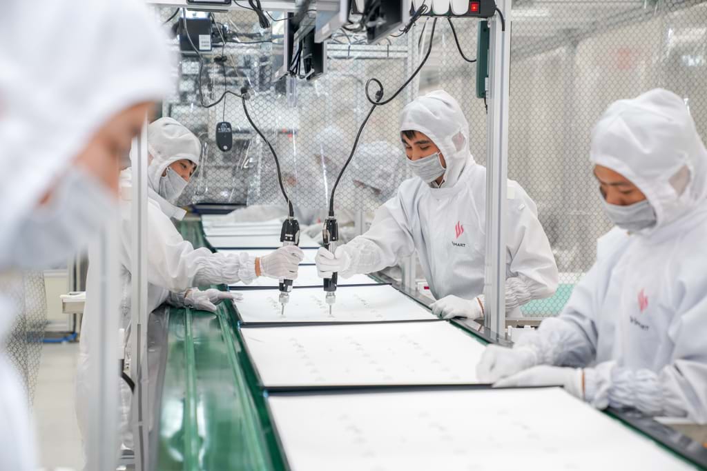 Những công nhân mặc đồng phục trắng đang làm việc trong xưởng sản xuất