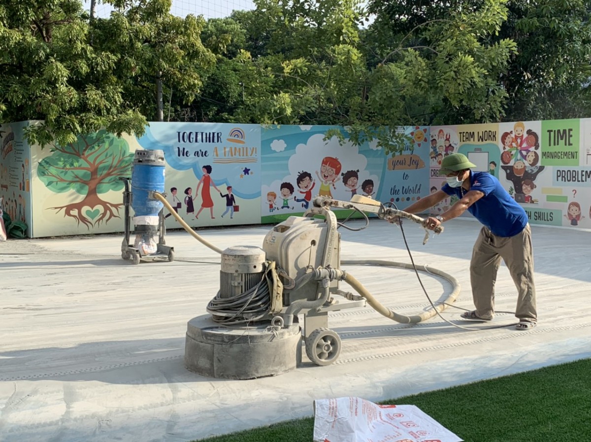 Một người thợ đang dùng máy mài công nghiệp để xử lý bề mặt để tiến hành quy trình sơn epoxy lăn