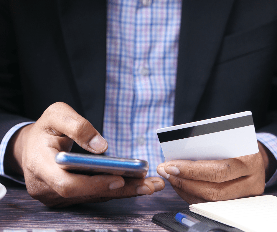 Một người đàn ông đang cầm điện thoại và thẻ ngân hàng
