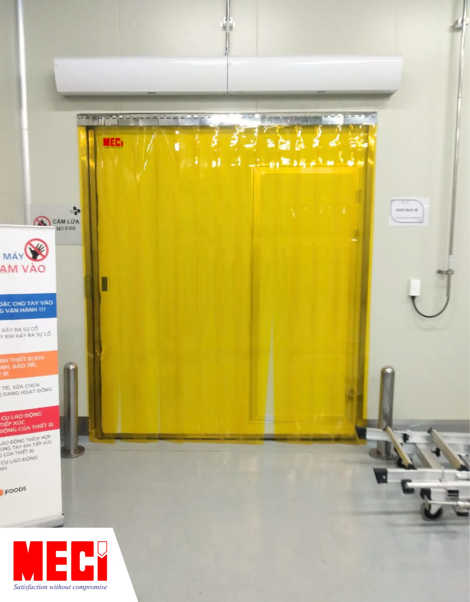 rèm nhựa PVC màu vàng được lắp kết hợp với cửa lùa trong phòng sạch, có hai chiếc quạt cắt gió phía trên