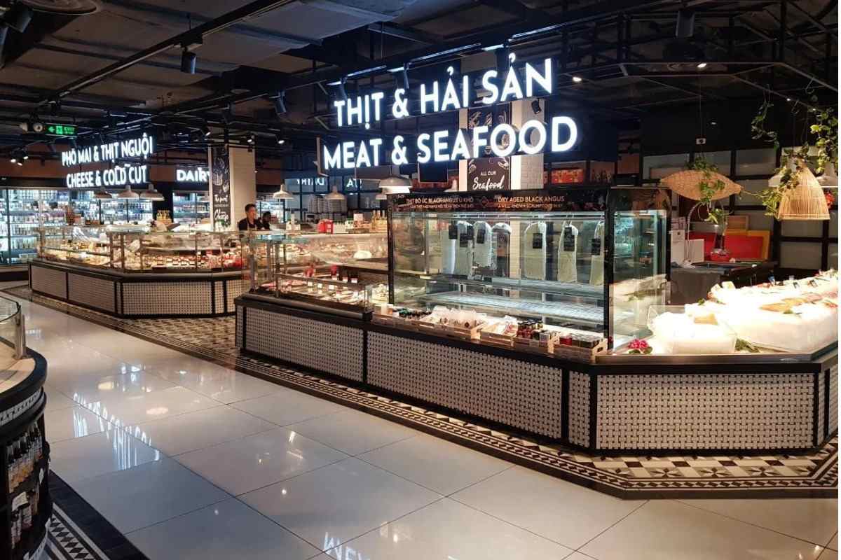 Hình ảnh mô tả không gian của siêu thị với sàn nhà sạch sẽ, lối đi rộng, khu vực sản phẩm được phân chia riêng biệt, ánh sáng tạo không khí dễ chịu khi mua sắm.