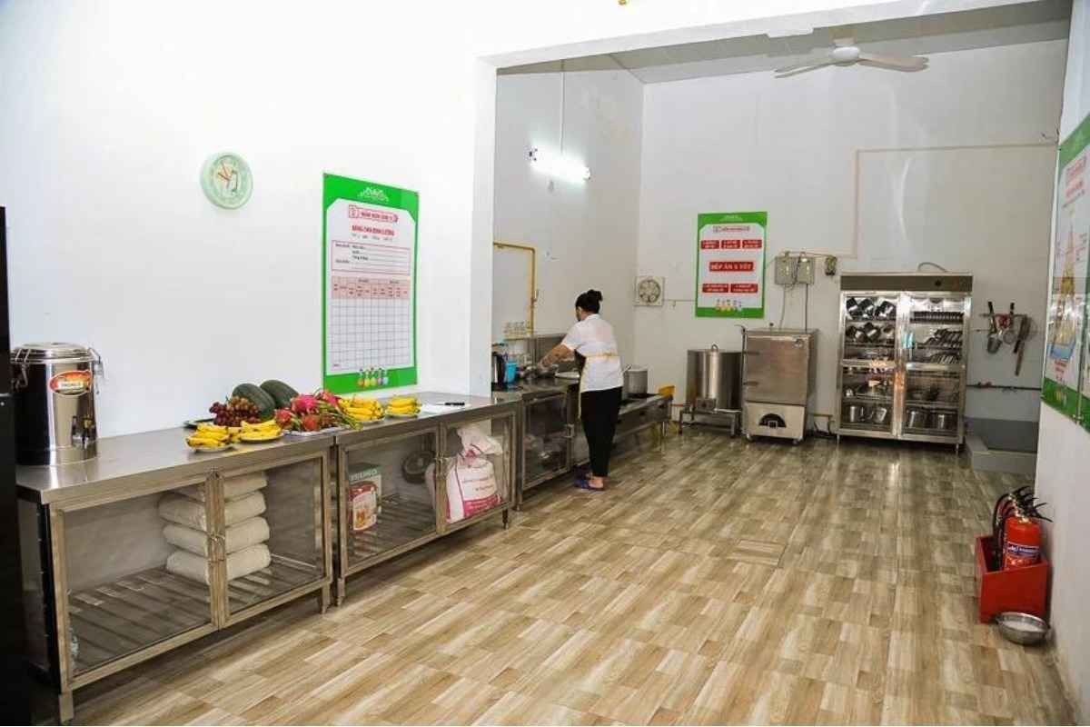 Cô giáo vụ đang nấu ăn cho trẻ và khu vực chia đồ ăn được tách biệt với khu nấu ăn