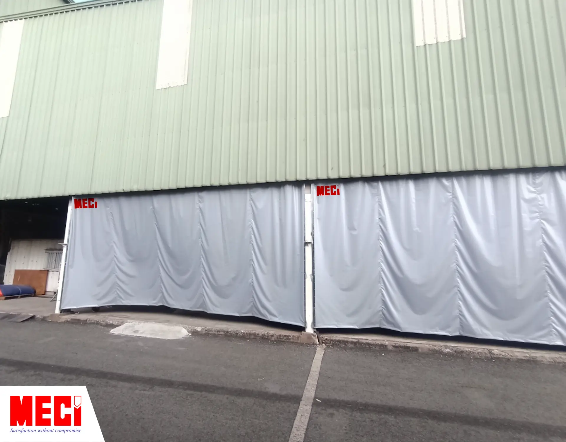 cái rèm kéo dạt màu xám được lắp bên ngoài một nhà xưởng