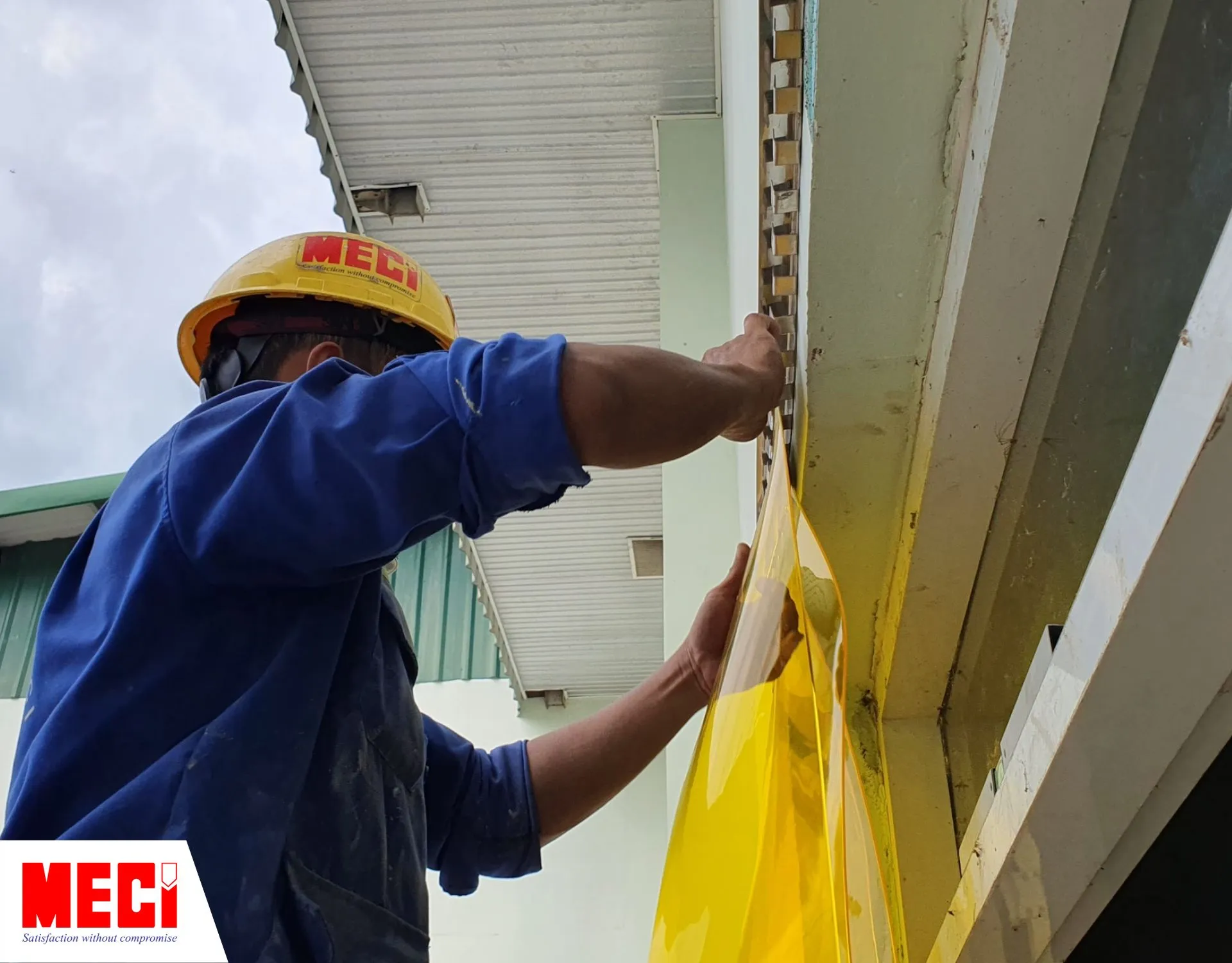 Kỹ thuật viên đang treo 1 sợi rèm nhựa PVC màu vàng lên thanh treo