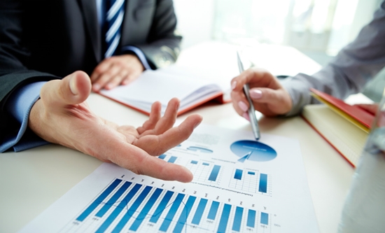 Hai người đàn ông đang ngồi chỉ tay vào biểu đồ trên bàn.