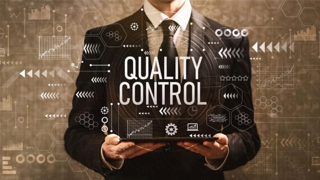 Hình ảnh có một người đàn ông mặc vest, trên tay là chiếc máy tính với nhiều biểu tượng như biểu đồ, máy móc, thiết bị, không gian số,.. và dòng chữ lớn QUALITY CONTROL.