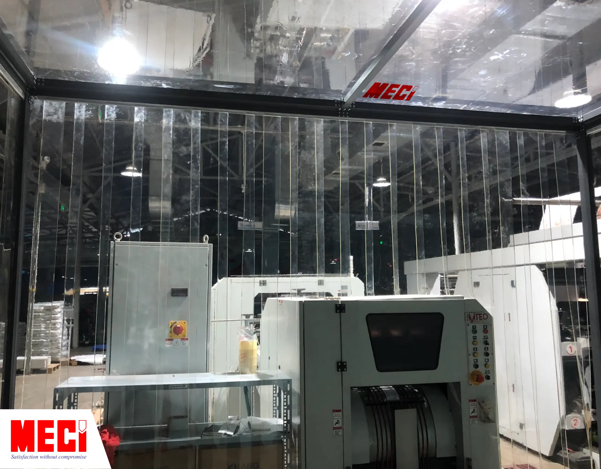 bên trong một căn buồng, phía trên là vách ngăn nhựa PVC, phía trước là rèm nhựa PVC thả sợi trong suốt thấy được nhiều máy móc bên ngoài