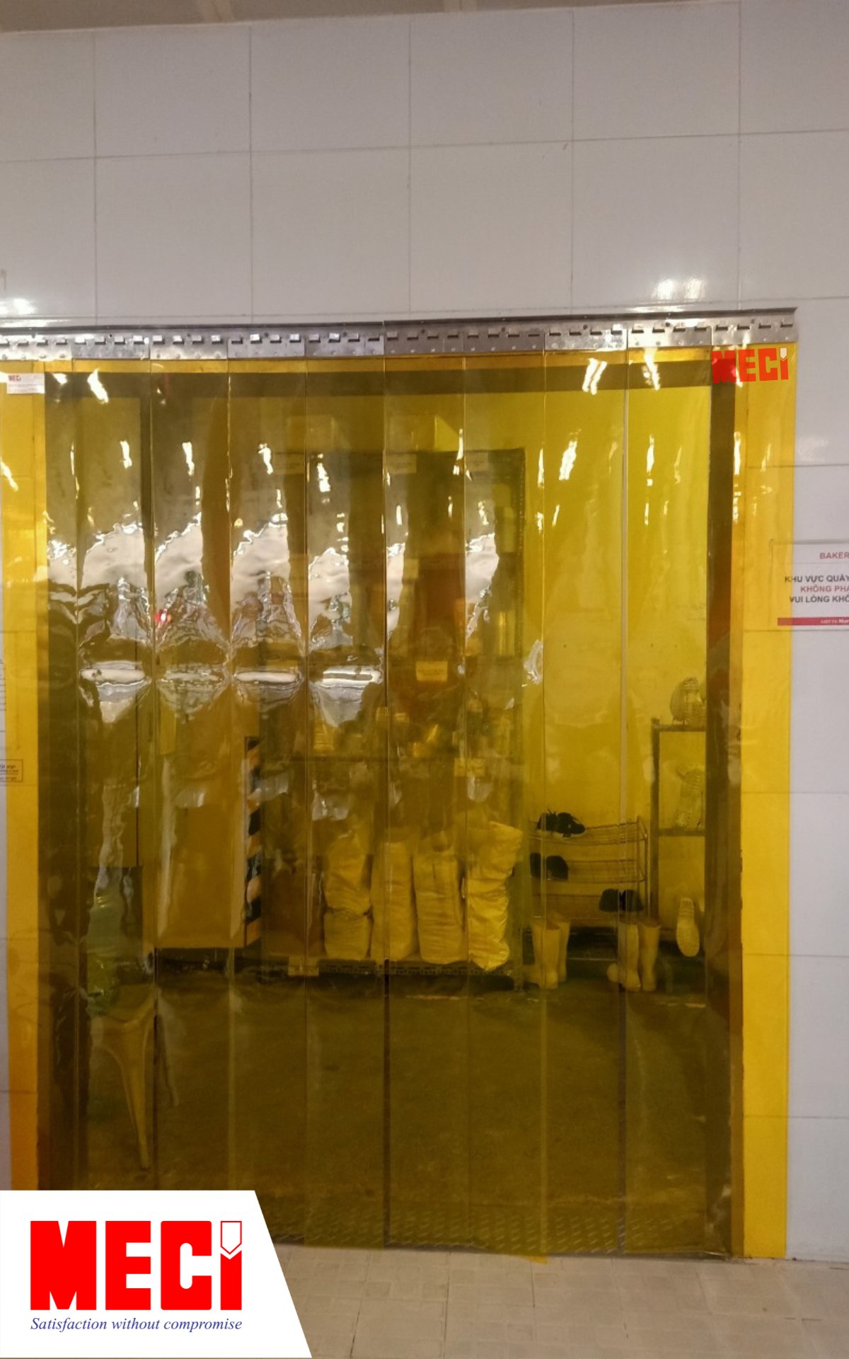 một cái rèm nhựa PVC màu vàng được lắp ở lối vào quầy bánh mì bên trong siêu thị