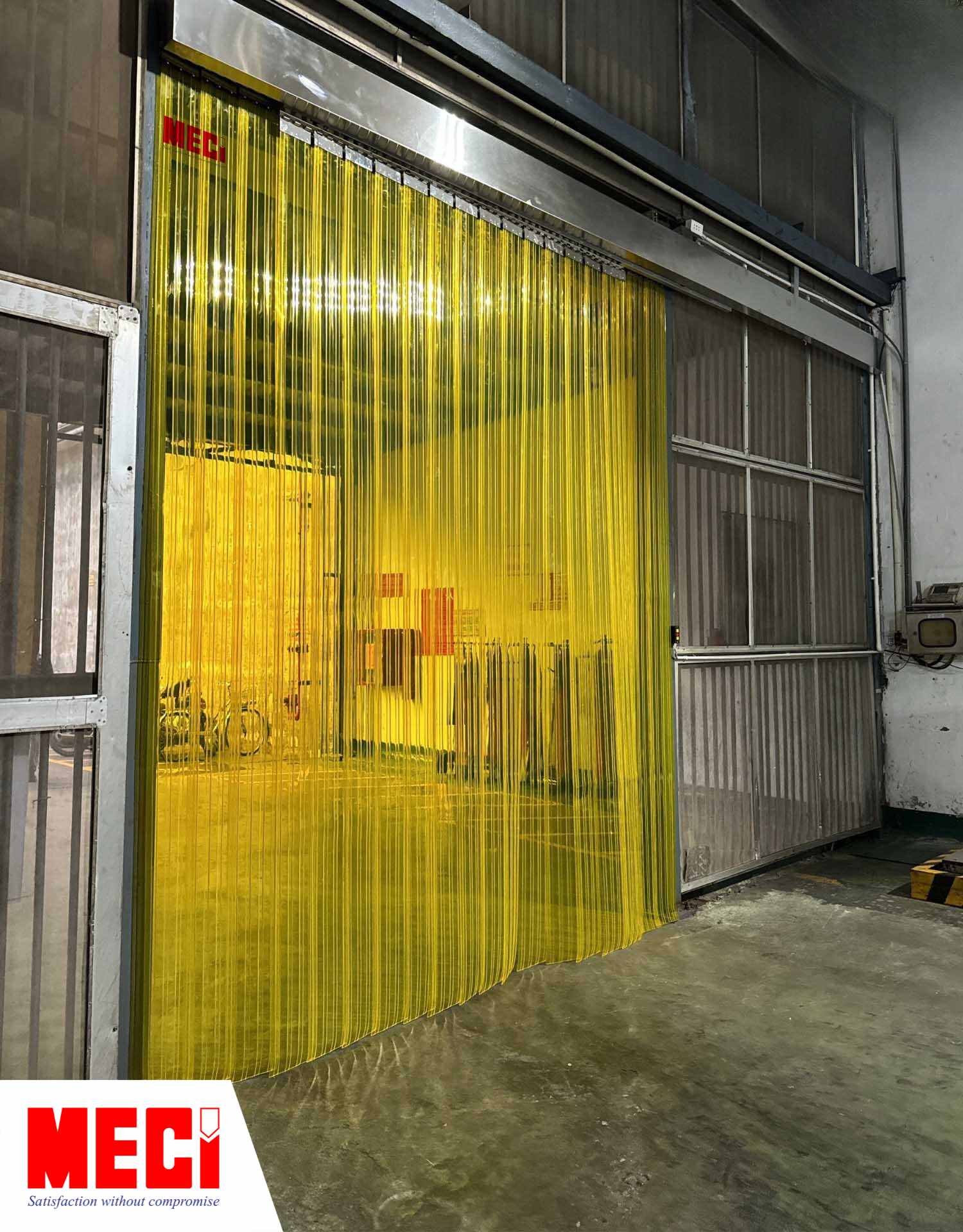rèm nhựa PVC màu vàng có sóng gân lắp tại một lối ra vào của một nhà máy