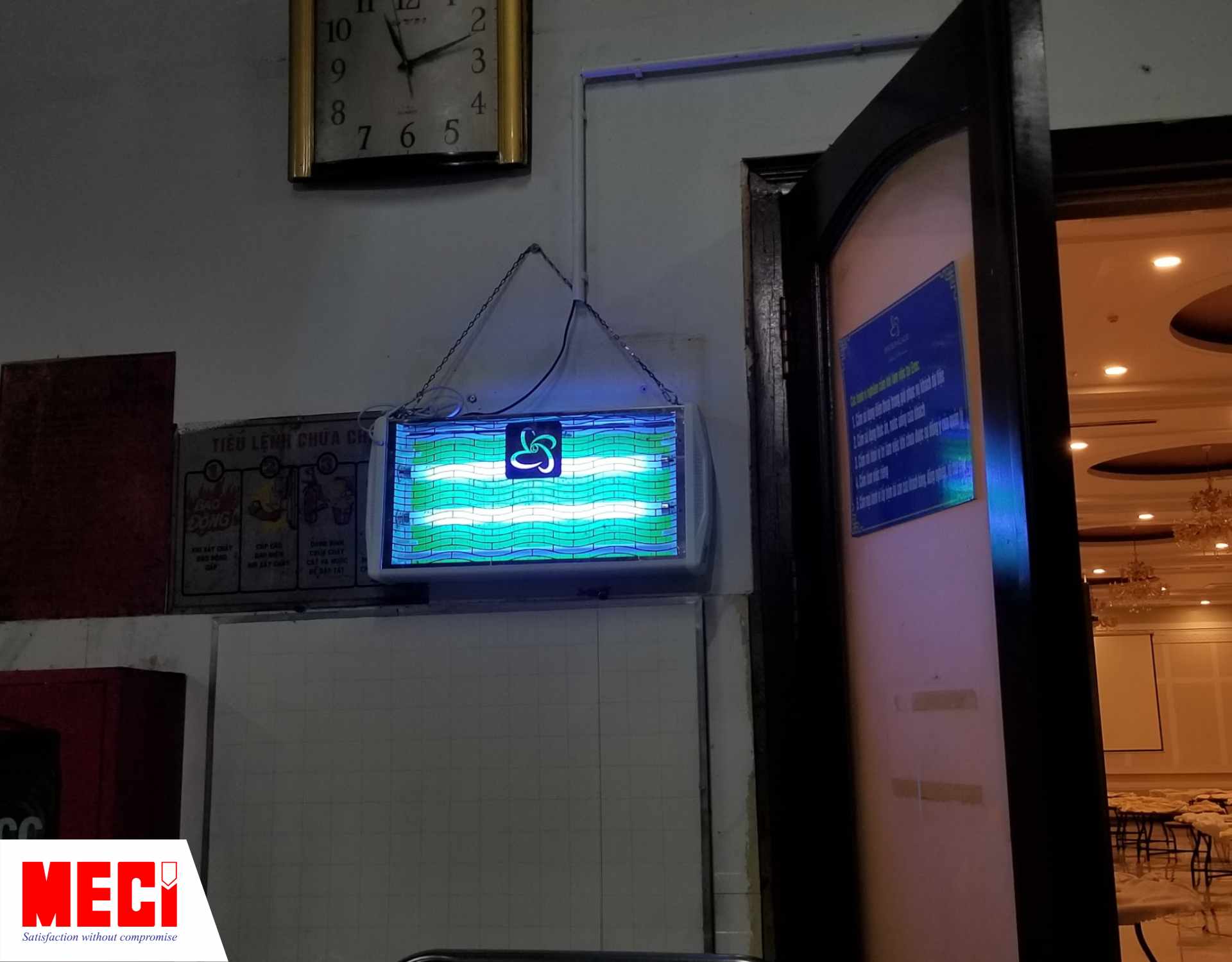 một cái đèn diệt côn trùng được treo bên cạnh cửa ra vào phòng tiệc, cánh cửa đang mở