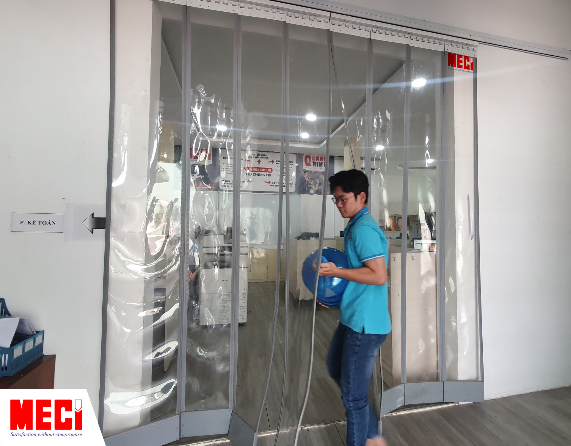 một người đang khuân thùng nước đi qua rèm nam châm