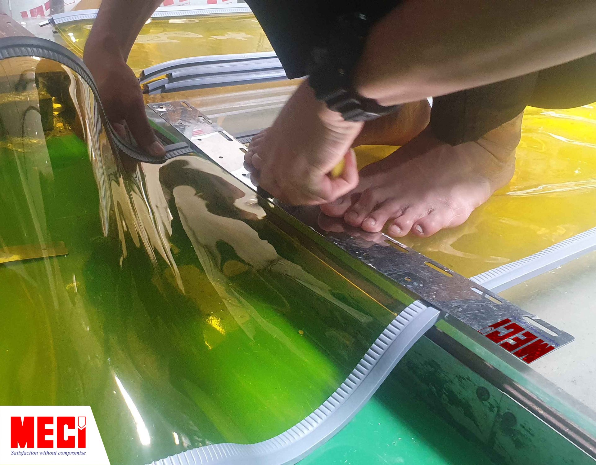 một bàn tay dùng thanh kim loại mỏng đè lên sợi nhựa PVC màu vàng có viền nam châm