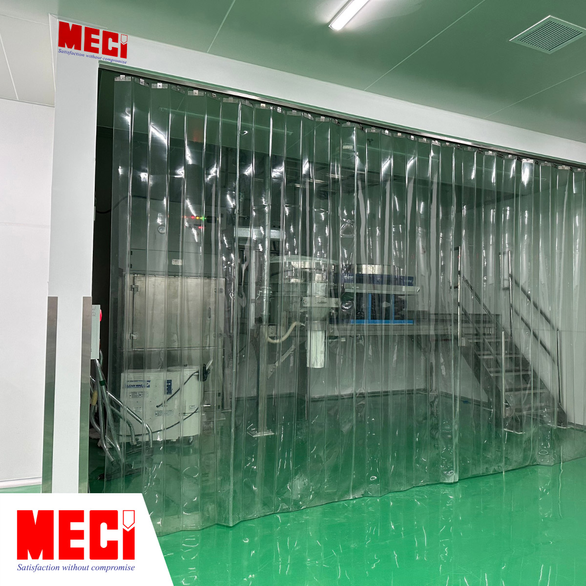 một căn phòng nhỏ ở góc nhà máy có nhiều máy móc bên trong, mặt trước căn phòng lắp rèm nhựa PVC xếp gấp màu xanh nhạt