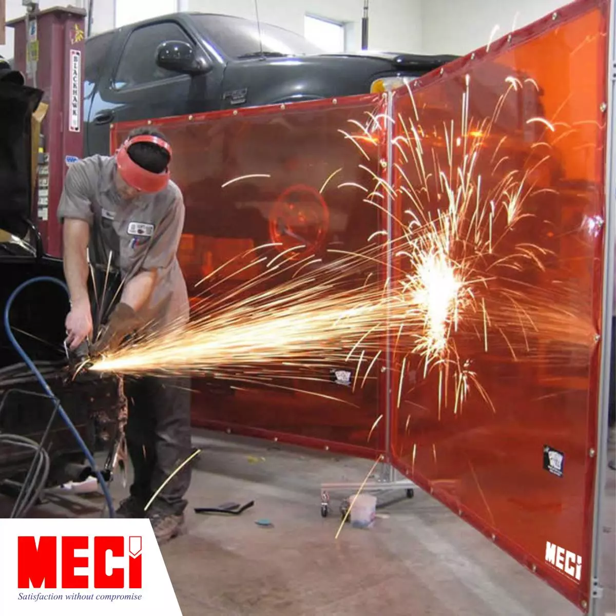 một người đàn ông đang đứng cắt kim loại, tia lửa hàng văng tung toé vài tấm vách ngăn màu đỏ