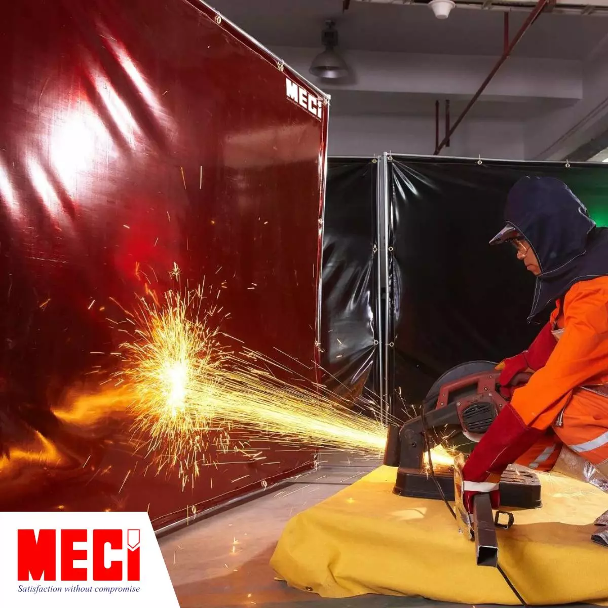 một người đàn ông mặc đồ bảo hộ đang cắt thanh kim loại, tia lửa hàng văng tung toé vào một vách ngăn