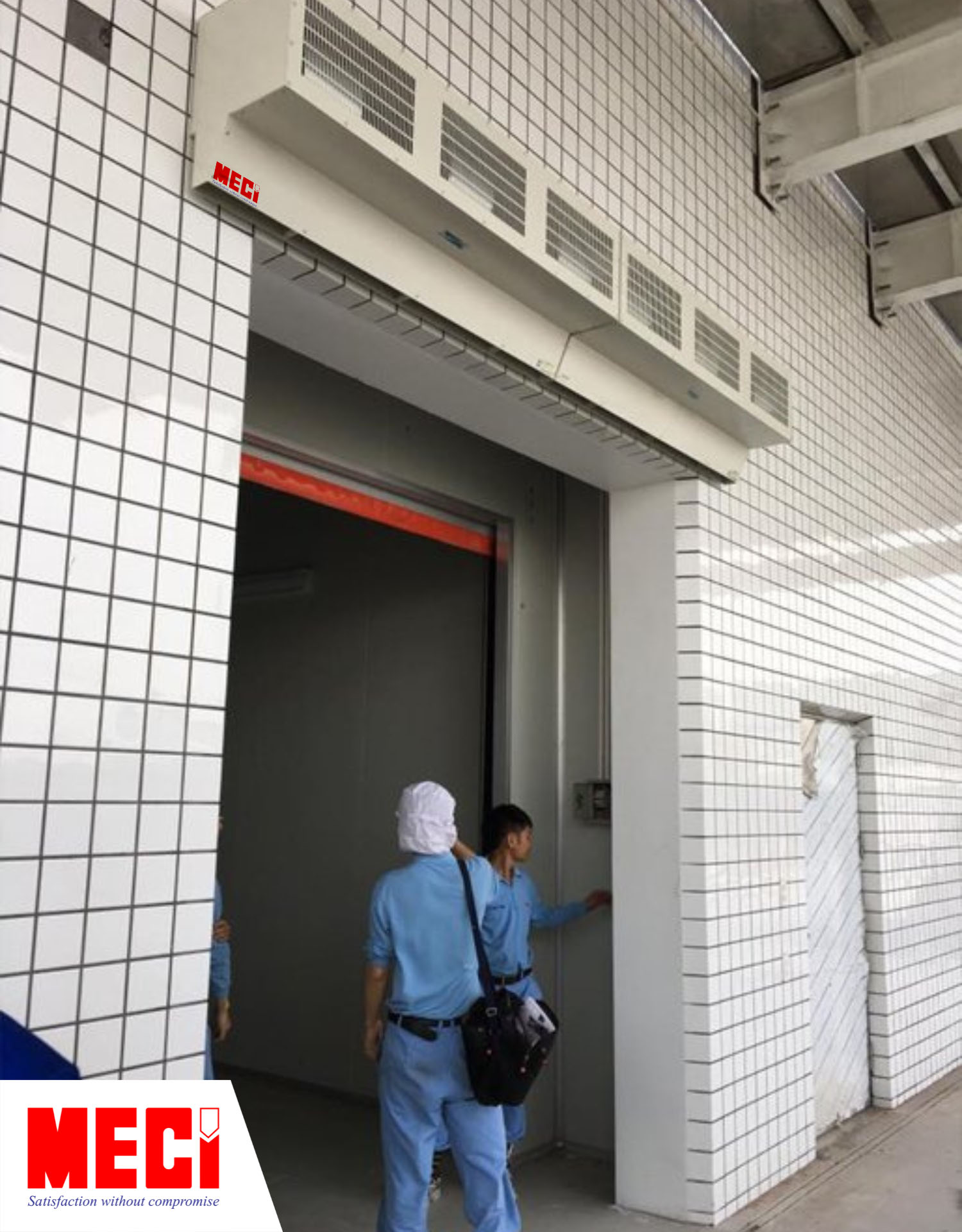 có hai người mặc áo xanh đang đứng ở lối ra vào, phía trên là quạt cắt gió công nghiệp lắp phía ngoài