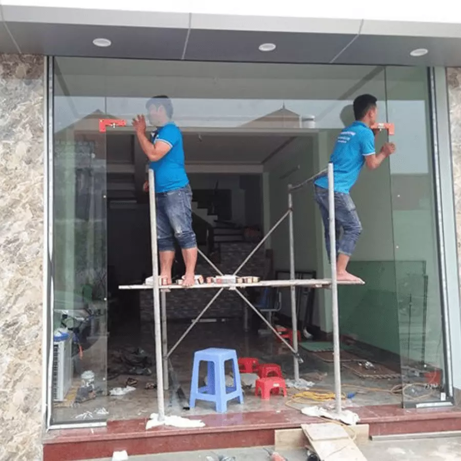 Hay người trên giàn giáo thi công cửa kính