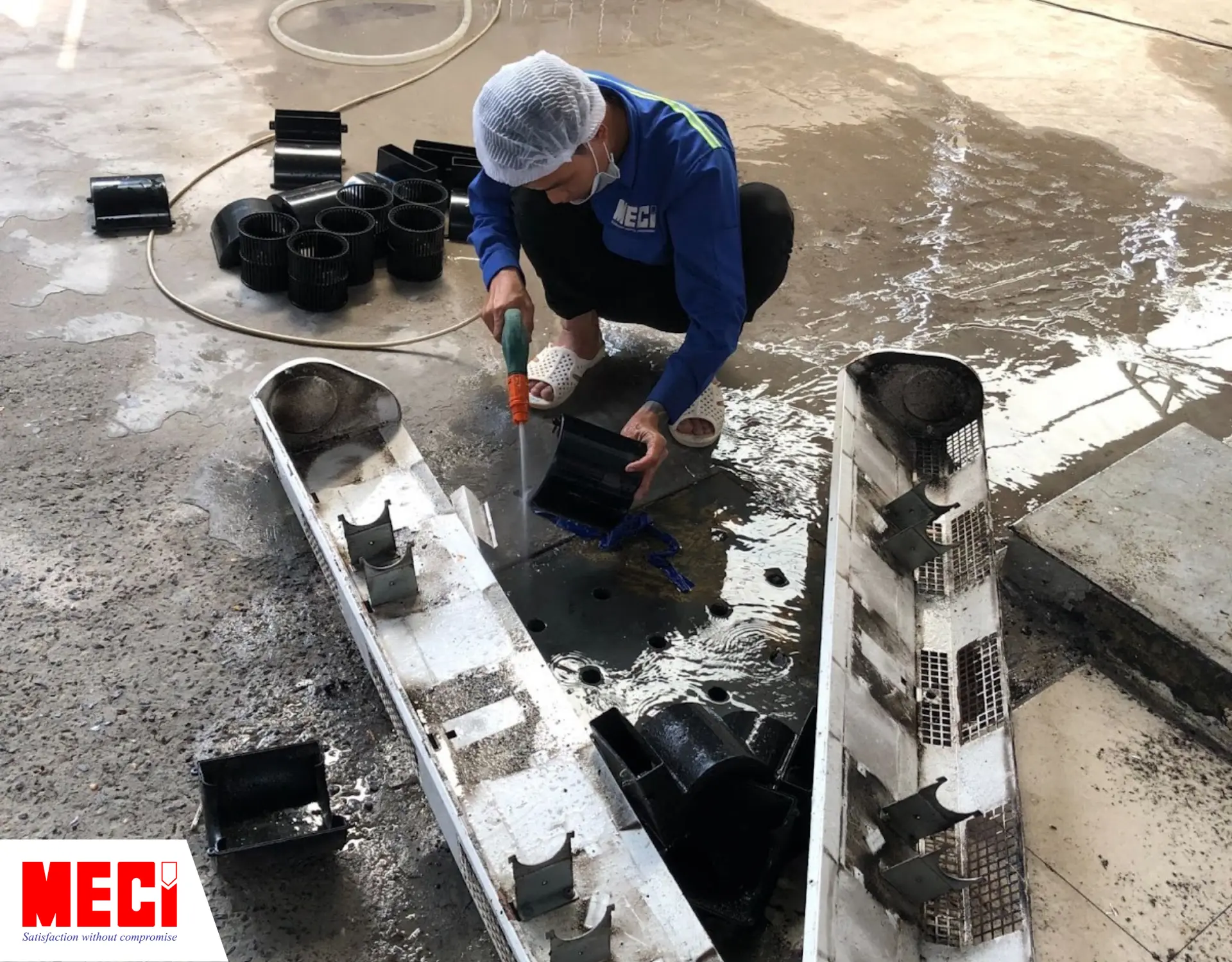 Kỹ thuật MECI đang sử dụng vòi phun nước để rửa từng bộ phận quạt