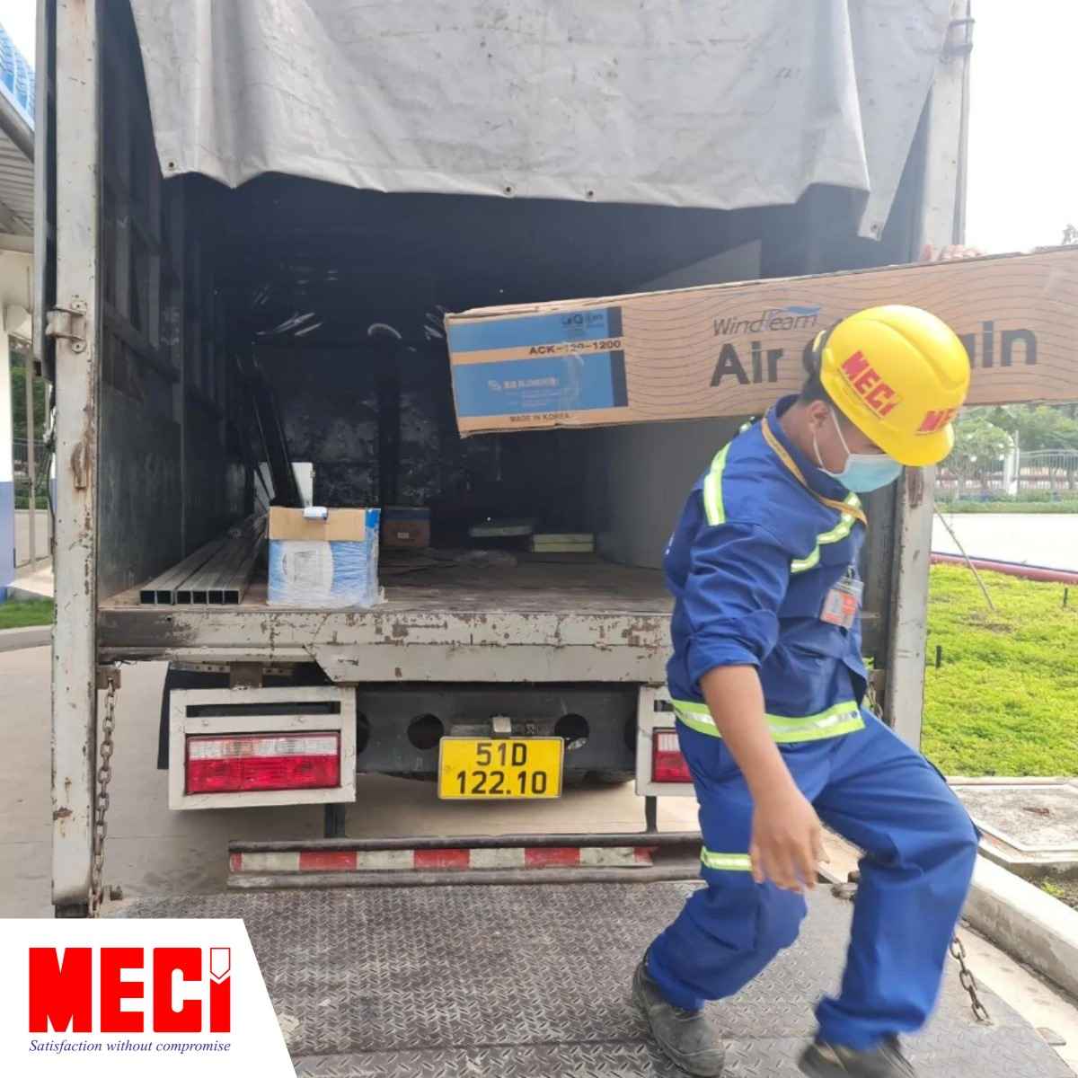 nhân viên MECI đang ôm quạt vào cho khách hàng, kế bên có xe tải