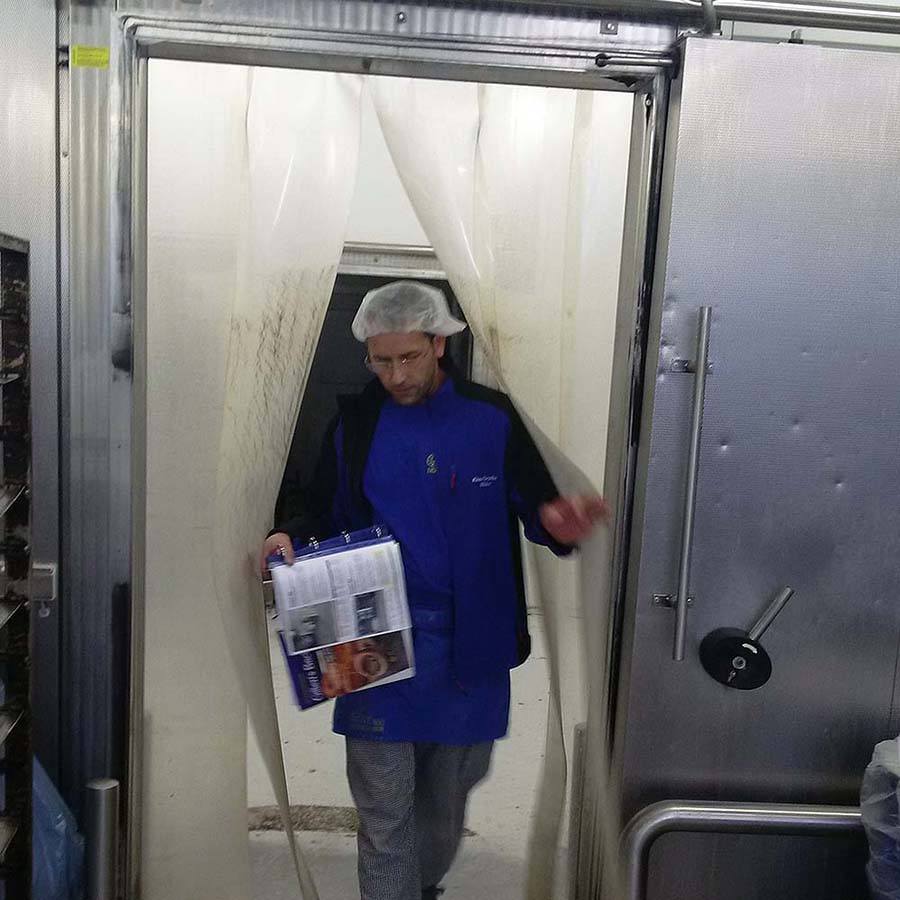 một người vén rèm nhựa âm sâu đi vào kho lạnh