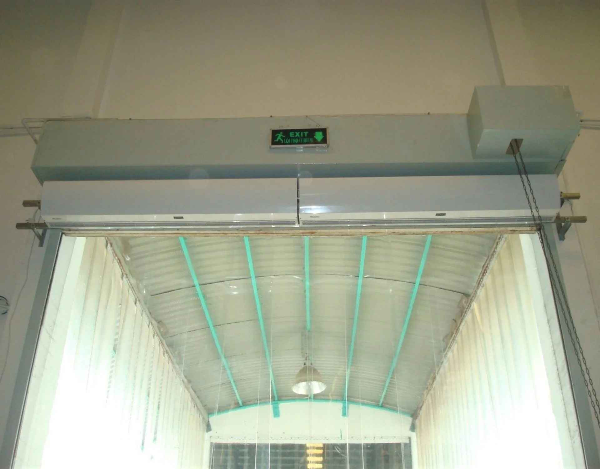 hai chiếc quạt cắt gió nedfon được lắp cạnh nhau phía dưới hộp cuốn cửa của cuốn, tại 1 lối ra vào nhà máy