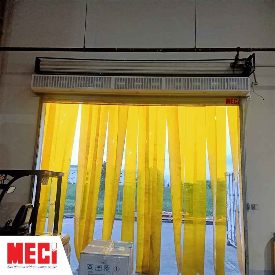 quạt cắt gió công nghiệp lắp phía trên lối ra vào, bên dưới treo 1 tấm rèm nhựa thả sợi màu vàng