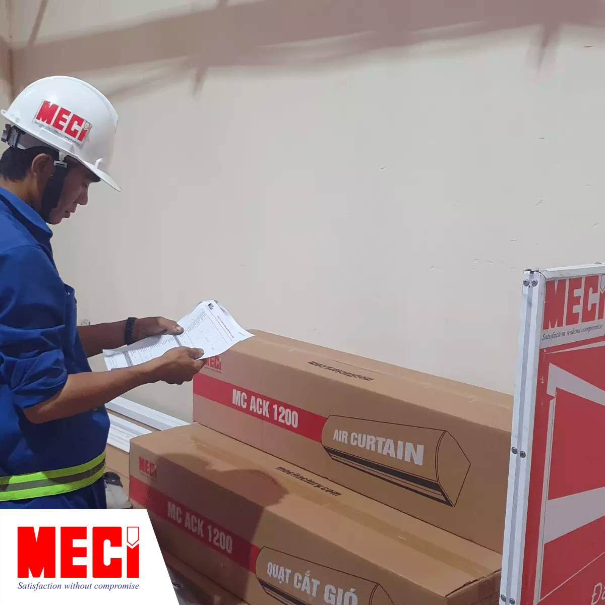 kỹ thuật nam đang đọc 1 tờ giấy trước các thùng carton đựng quạt cắt gió