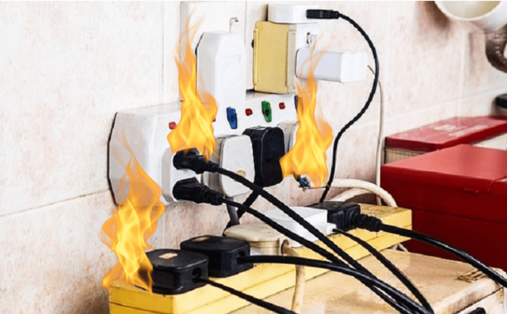 Hình ảnh các ổ cắm điện được cắm bởi nhiều phích cắm trên kệ màu vàng. Lửa bốc lên tại các phích cắm đó.