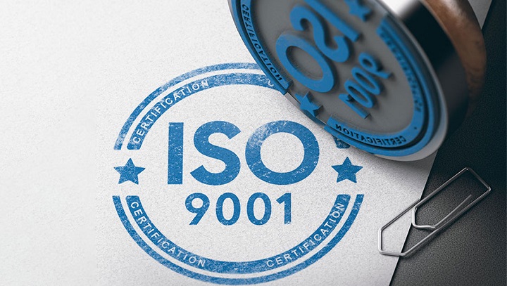 Dấu mộc màu đen in trên giấy chữ ISO 9001 màu xanh. Bên cạnh có ghim giấy.
