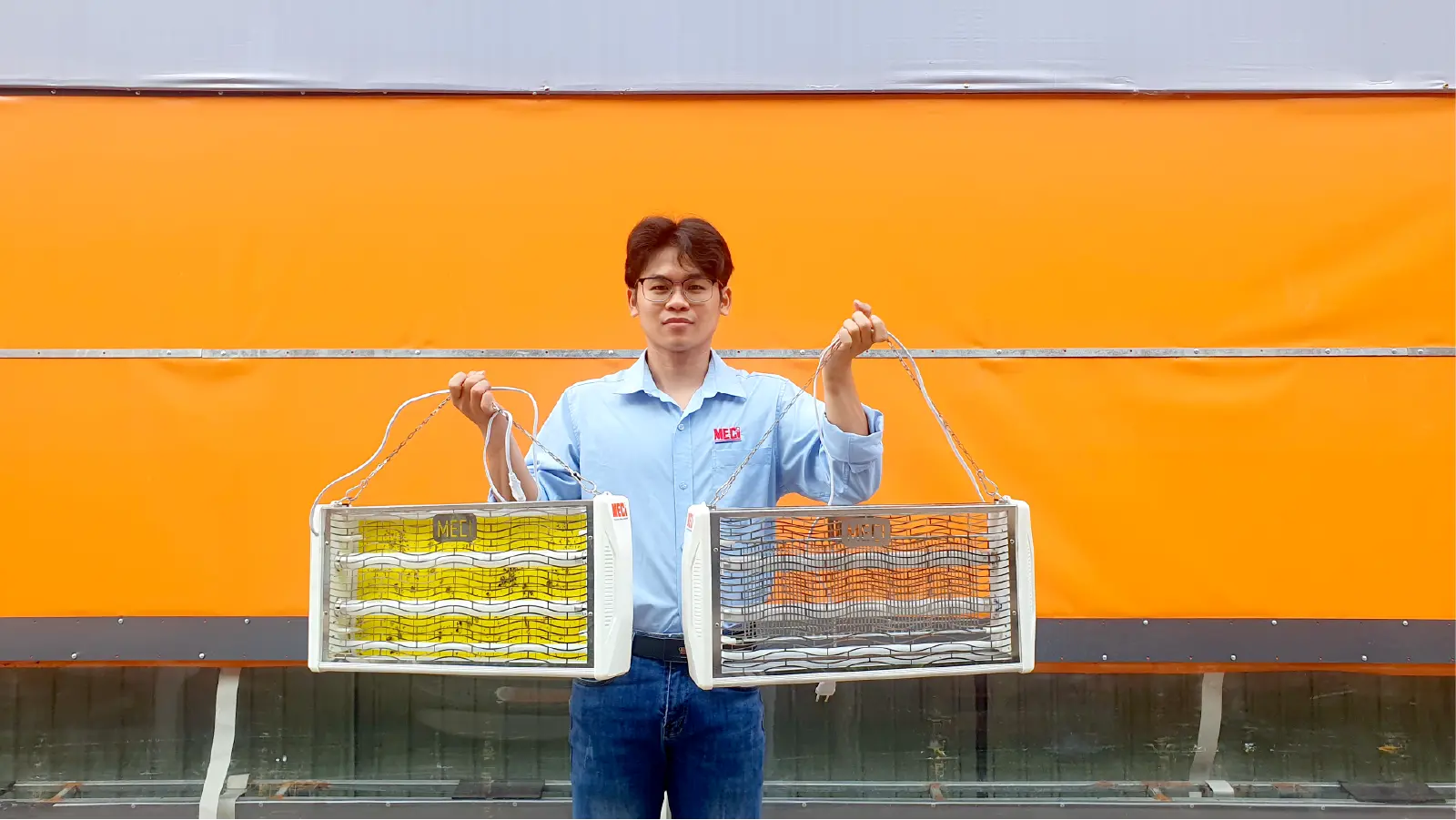 Nhân viên MECI đang cầm 2 chiếc đèn diệt côn trùng bằng keo và điện