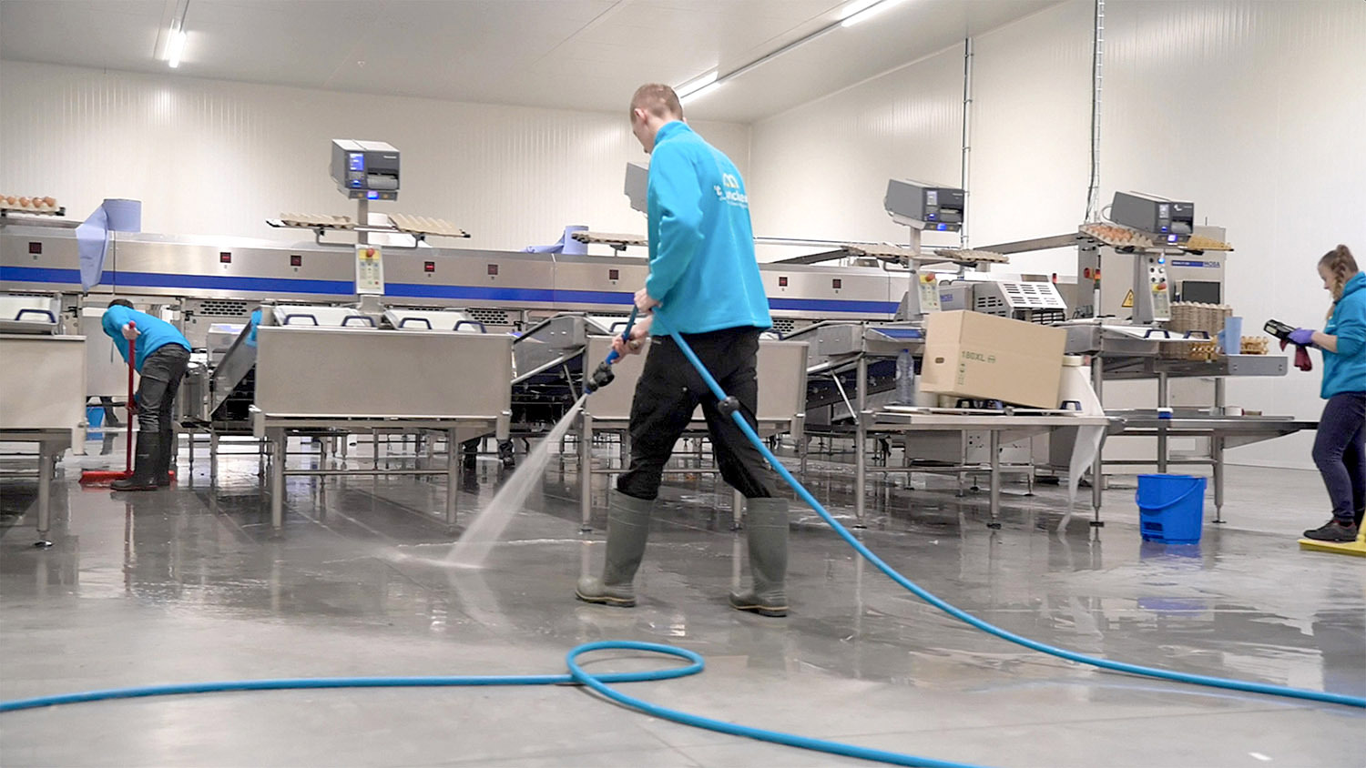 Một nhân viên đang dùng vòi nước xịt lên sàn nhà xưởng