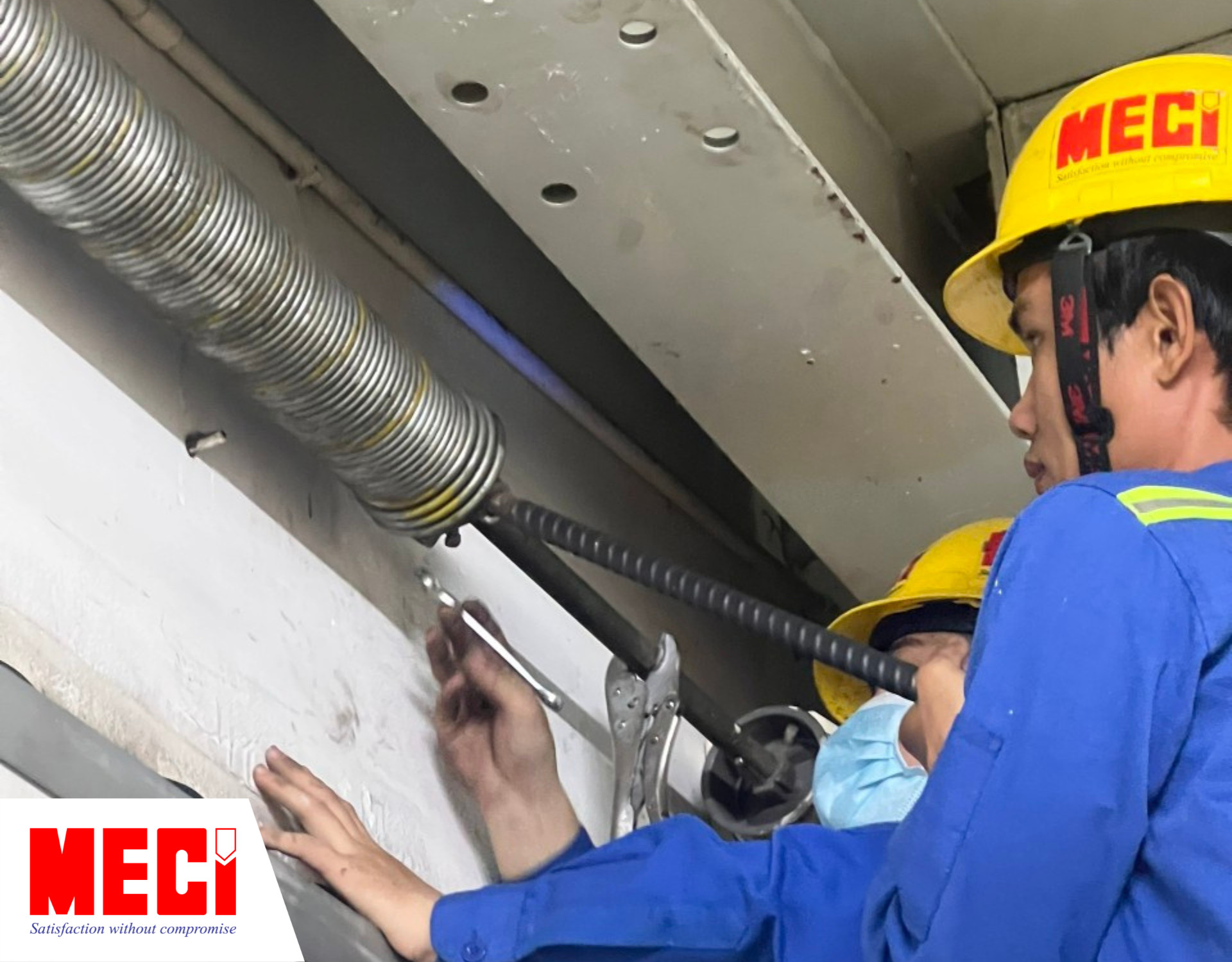 Hình ảnh thực tế của Dự án bảo dưỡng định kỳ tại DKSH, kỹ thuật đang tra dầu nhớt vào trục lò xo - một trong những quy trình bảo trì cửa trượt trần