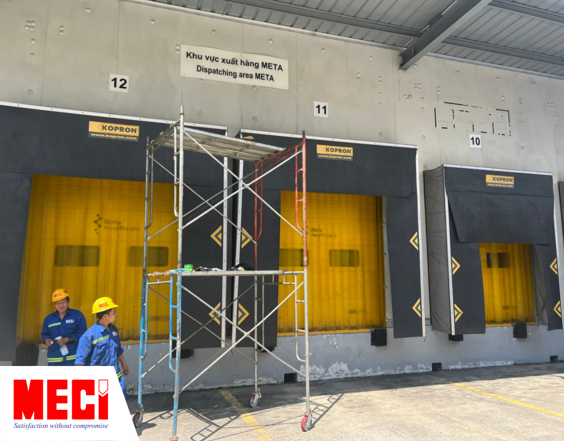 hai kỹ thuật đứng cạnh giàn giáo trước 3 dock giao nhận hàng có rèm vàng và dockshelfter